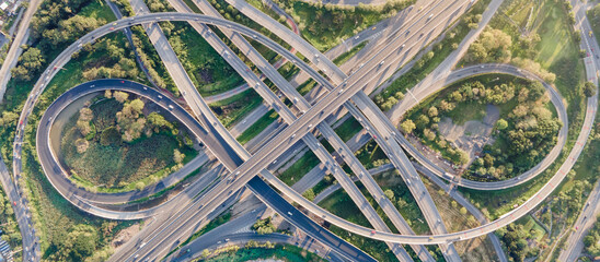 Aerial view of road interchange or highway intersection with busy urban traffic speeding on the road. Junction network of transportation taken by drone.