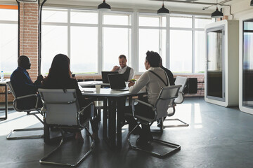 Group of young business people working and communicating while sitting at the office desk together with colleagues sitting. business meeting
