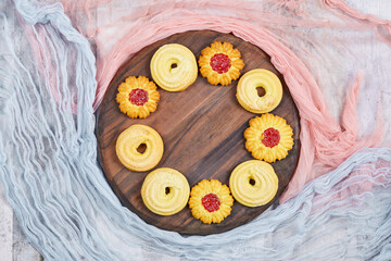 Assorted biscuits on the wooden plate with pink and blue tablecloths