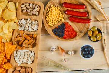 Assorted snacks, a plate of sausages, caviar, and olives on a wooden table