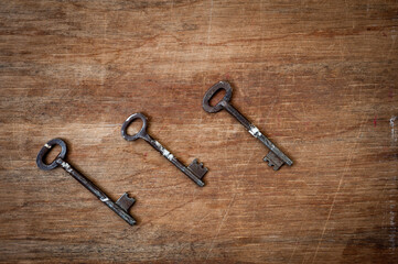 Old iron door keys lying on an old wooden surface.