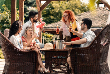 Group of young people having fun at summer vacation and enjoying a poolside party with drinks.
