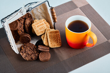 Assorted biscuits, candies and a cup of tea on gray background