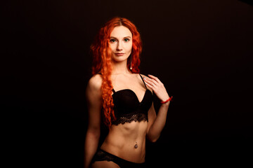 Fototapeta premium Sexy woman in lingerie in black background, red hair