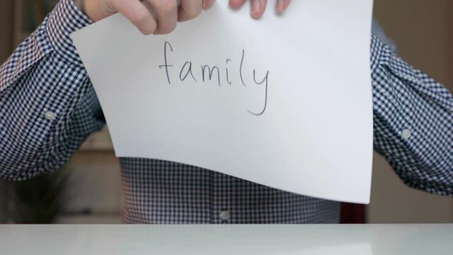 a man tears up a piece of paper with the word family on it. words family are written on a piece of paper. the family broke up