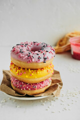 three beautiful multicolored very appetizing glazed donuts on a plate, vertical food content, selective focus