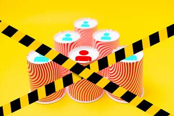Paper cups arranged in a pyramid shape, with the image of the little man's symbols on the bottom. Blocked by a barrier tape. The concept of business management and career