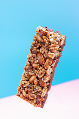 Protein bar with cereals on pink and blue background