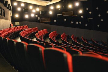 Cinema interior. Red armchairs in a large empty cinema hall and special illumination on the walls....