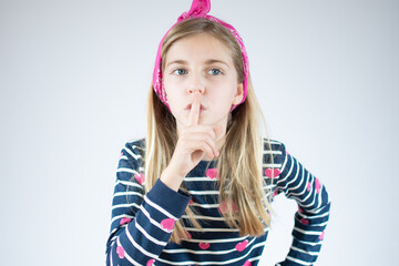 Closeup portrait of blonde girl putting finger up to lips isolated on white background