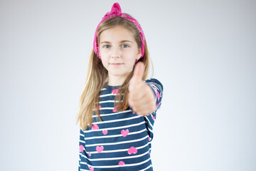 Happy Young girl in striped shirt and showing thumb up and looking at the camera over white background