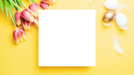 Egg color. Happy Easter decoration: golden colour eggs in basket with spring tulips, white feathers on pastel yellow background. Foil minimalist egg design, modern top view template.