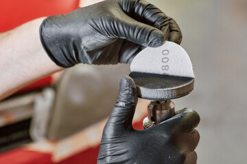 gloved human hands placing sandpaper on a polisher. abrasive discs. polishing tools and work concept