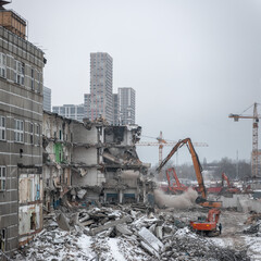 Demolition of an old industrial building in Moscow on a overcast winter day with a new high-rise residential building in the background
