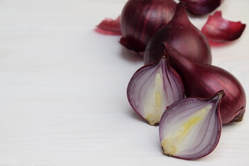 Red onions with onion cut in half on white wooden background