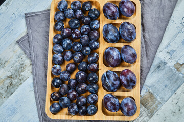 Garden plums on wooden platter with gray tablecloth