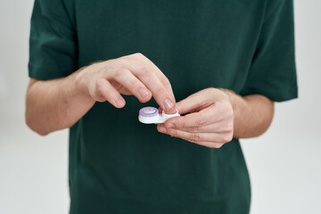 Fototapeta premium Man taking out contact lenses from storage box