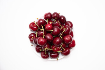 a pile of ripe red cherry berries lies on a white porcelain bowl background image on a white background without people close up