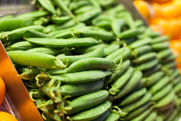 green fava beans in pods on counter in market