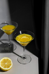 Orange juice or lemon alcohol cocktail in glasses on the marble table. Yellow and grey trendy colors of 2021 years still life