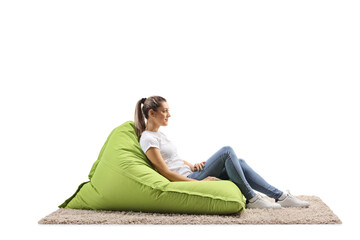 Profile shot of a casual young woman sitting on a green bean bag armchair