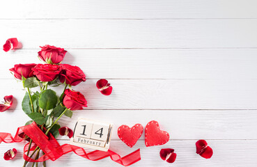 Love and Valentine's day concept made from red hearts, wooden calendar and rose on white wooden background. Top view with copy space, flat lay.