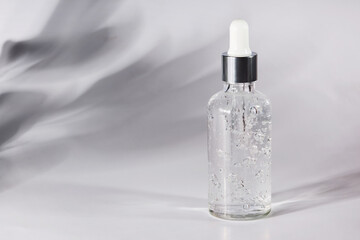 Anti aging serum in a glass bottle on a gray background. Facial liquid serum with collagen and peptides. Natural skincare essence for beautiful healthy skin. 