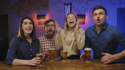 Friends in pub drink beer on bar counter, watch sport game on tv and celebrate goal of the team. Overjoyd peeple screem and get exited.