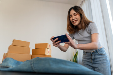 Obraz premium Asian online merchants take photos of denim shirts ready to be sold online. Work from home concept.