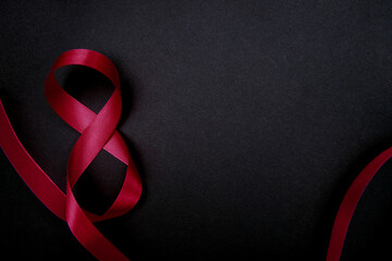 On a black background, a pink satin ribbon in the form of the number eight. The concept of March 8 and Valentine's Day.