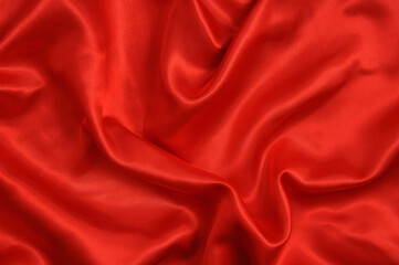Background red satin fabric with folds. Curtains and textiles.