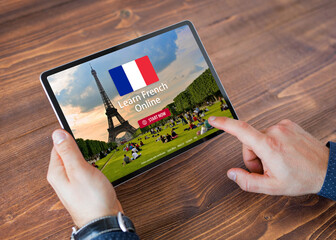 Person taking online courses on tablet to learn French language