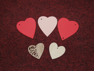 Five hearts made of wood, red, pink and natural wood. Valentine's day. on a burgundy background.