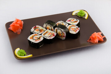 Complex roll - hot and cold with salmon, flying fish roe and avocado on white plate on black background