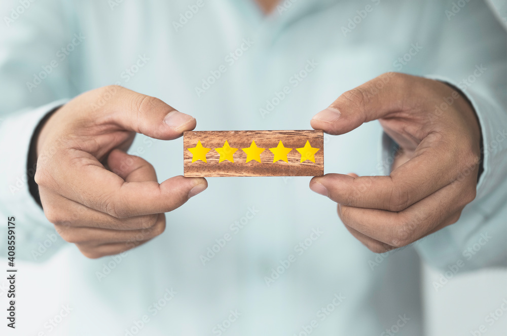 Poster businessman showing yellow five stars which print screen on wooden block cube foe customer evaluatio