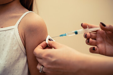 Little girl in the doctor's office is vaccinated. Syringe with vaccine against covid-19 coronavirus, flu, infectious diseases. Injection after clinical trials for human, child. Medicine concept.