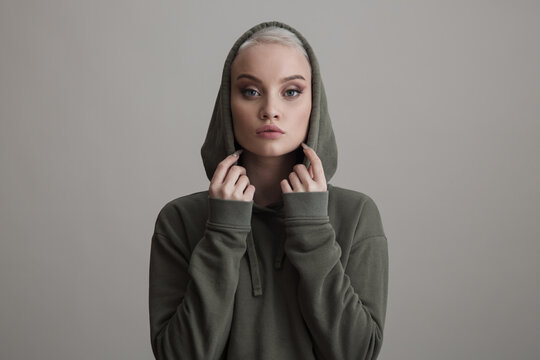 Beautiful young girl dressed in a hoodie on a gray background