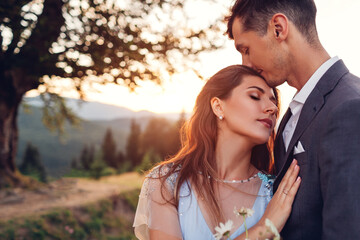 Loving wedding couple hugging in mountains at sunset. Portrait of bride and groom in summer Carpathians. Valentine's day