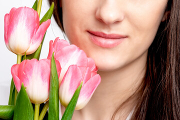 Half face portrait of a happy young caucasian woman with pink tulips against a white background