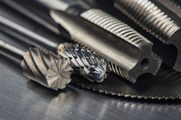 set of different drill bits,thread tap and mill cutters with caliper ruler on steel plate...