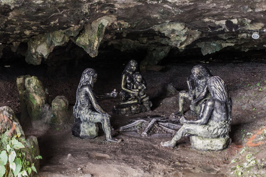 FURONG ZHEN, CHINA - AUGUST 11, 2018: Sculptures of prehistoric people in a cave under the waterfall in Furong Zhen town, Hunan province, China