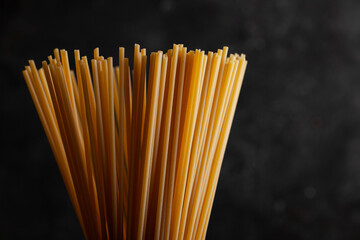 Bunch of dry spaghetti on dark concrete background with copy space. 