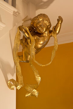 Gold ribbon trailing over cherub figure in corner of room