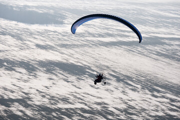 Paragliding motorized or paramotor buggy seen from the sky in France flying over snowy fields in winter