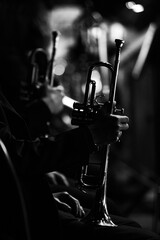 Silhouette of a trumpet in the hands of a musician in an orchestra in dark colors - obrazy, fototapety, plakaty