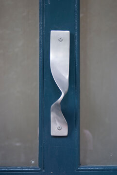 A matt silver iron handle on a blue door.