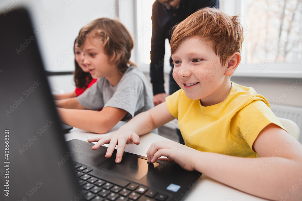 Wall mural excited boy working with laptop in classroom