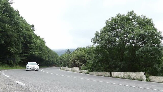 Sevan, Armenia - August 2019. Cars ride on a flat asphalt road in the middle of the forest - Time Lapse