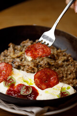 Boiled buckwheat with mushrooms and tomatoes on a wooden background. Dish in a frying pan close-up.