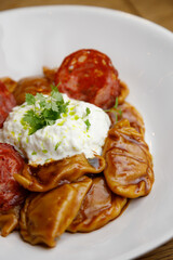Traditional steamed dumplings with tomato sauce and sour cream. Restaurant serving dishes close-up.